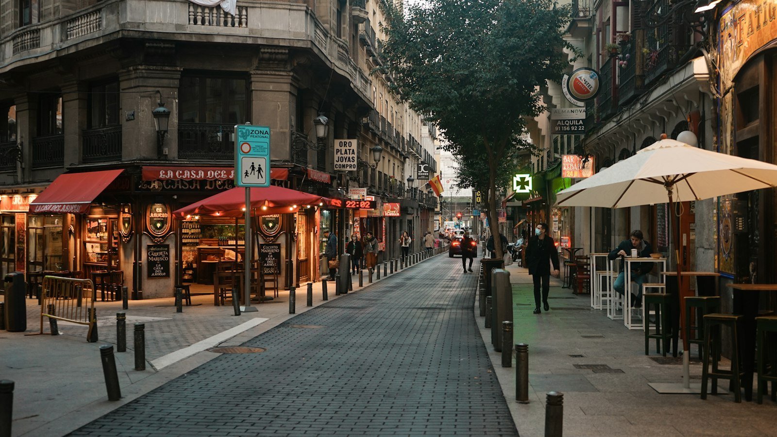 Personas caminando por una calle de barrio junto a un edificio