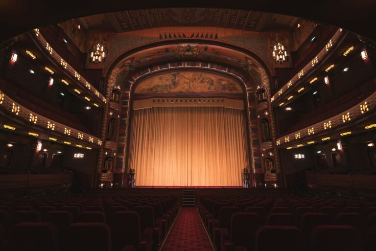 Teatro vacío con butacas rojas y cortina dorada
