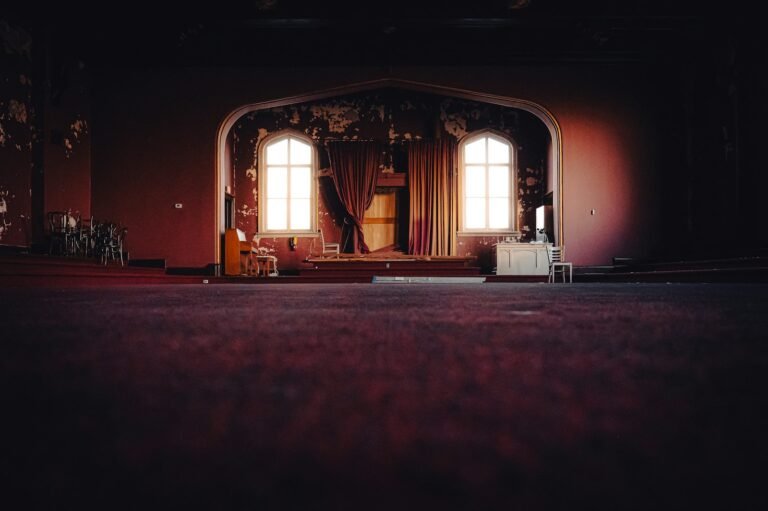 Escenario de teatro vacío con ventanas arqueadas y cortinas